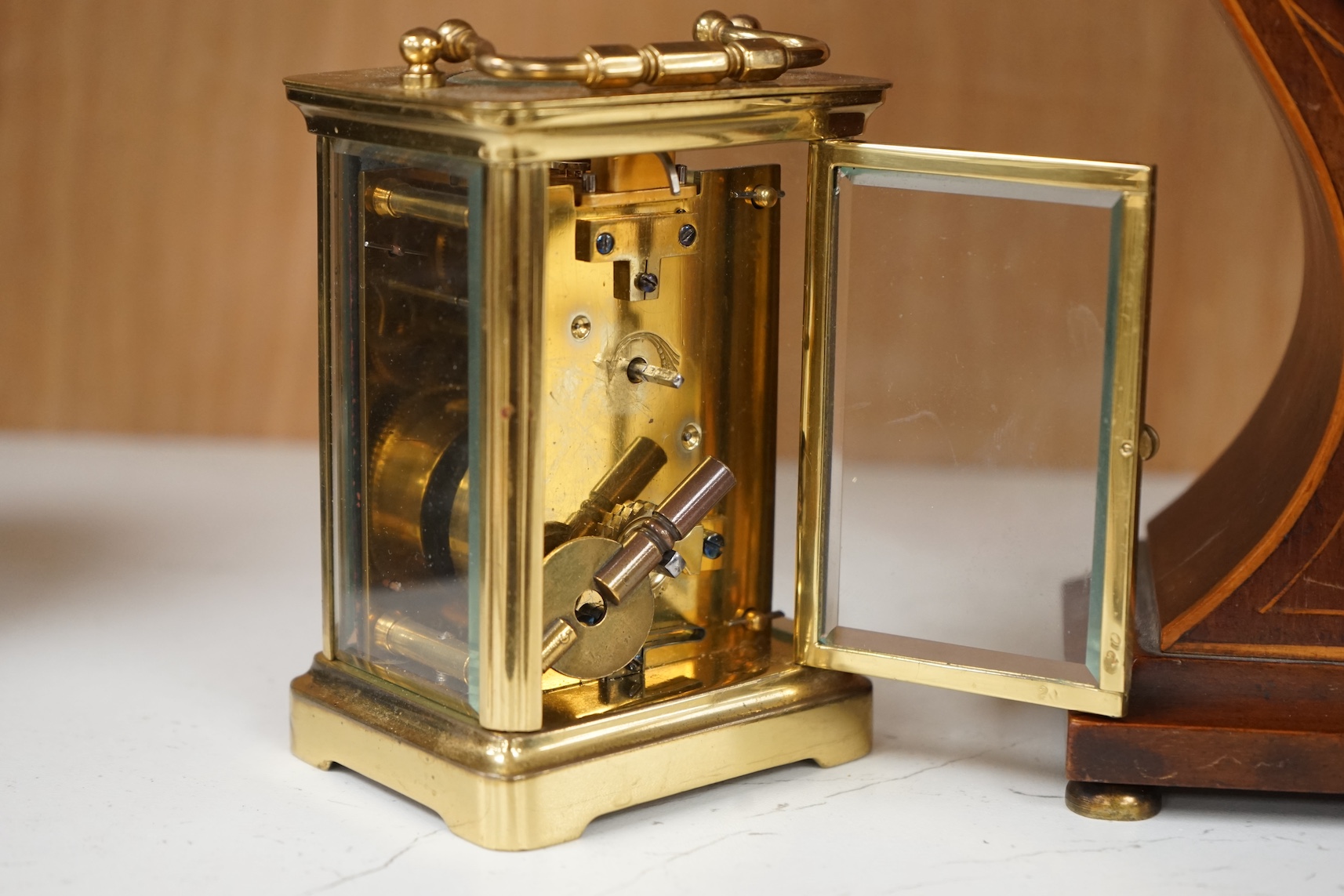 An Edwardian inlaid mahogany balloon clock and a brass cased carriage timepiece, largest 23cm high. Condition - fair, untested